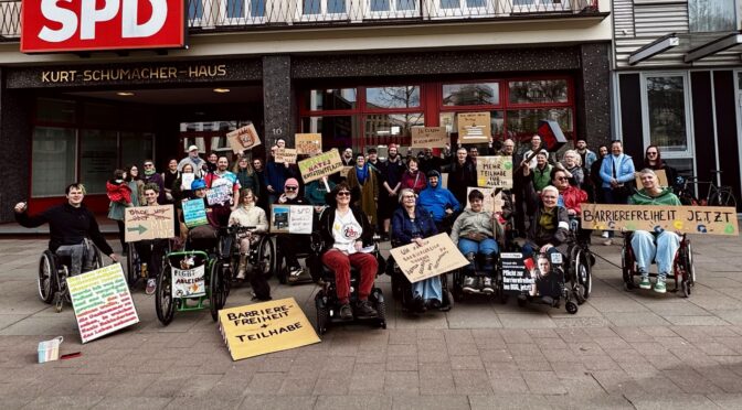 Gruppenbild bei der Demo vor der SPD Zentrale in Hamburg. ca. 40 Menshcen mit Plakaten, Und eine Rampe aus Pappkarton und einen "BGG" Hammer